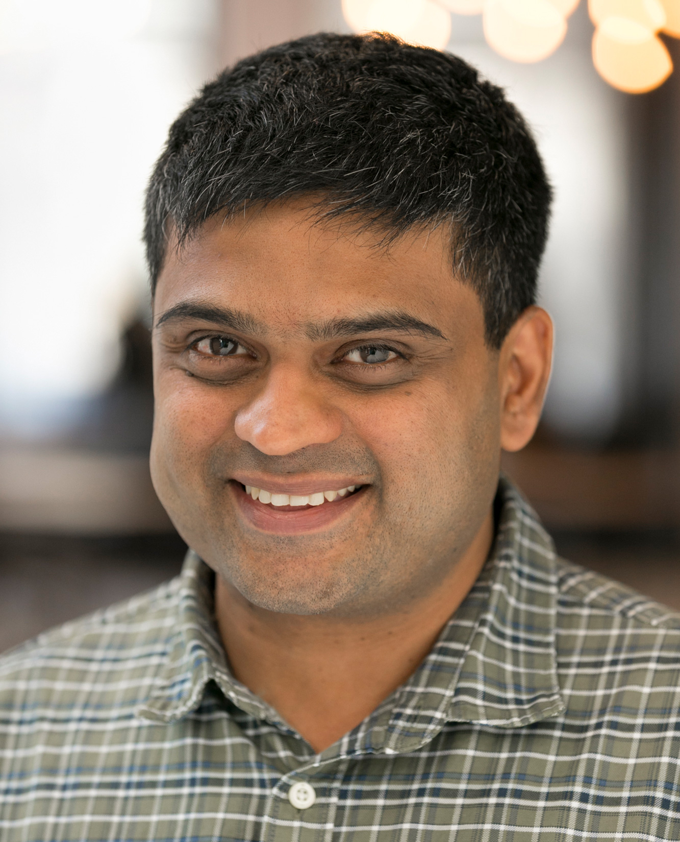 A smiling man in a checked shirt.