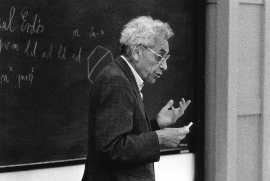 Black-and-white photo of Paul Erdős in front of a chalkboard; black-and-white photo of András Hajnal seated indoors