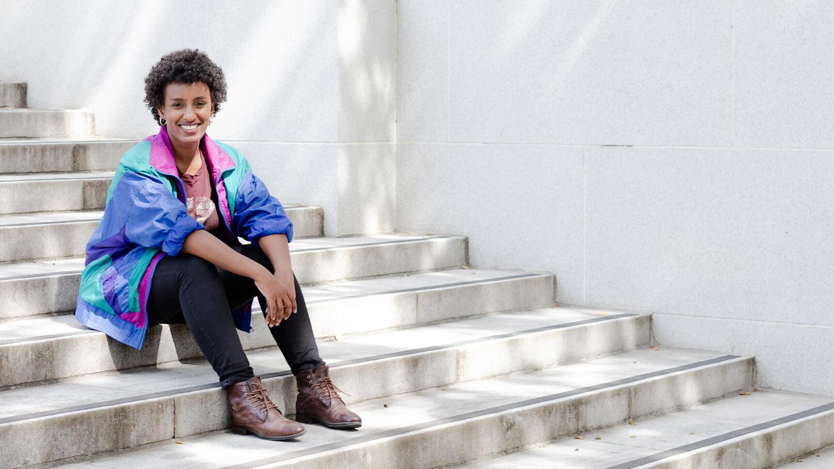 Rediet Abebe sitting on steps outside on the University of California, Berkeley campus.