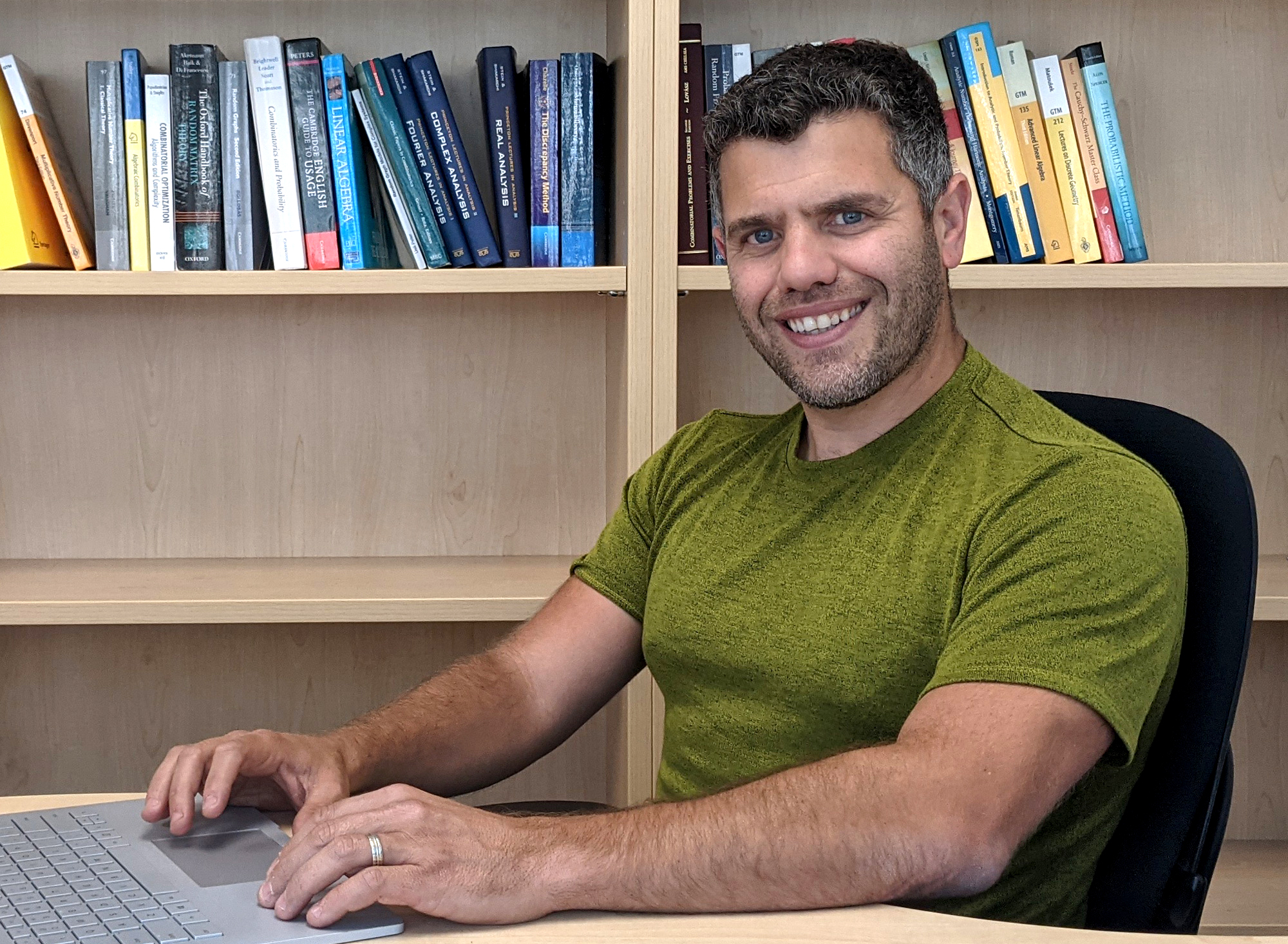 An outdoor photo of Michael Krivelevich in a purple shirt; a photo of Asaf Ferber in a green shirt sitting at a laptop