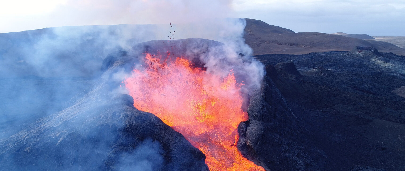 Lava bubbling out of the top of a volcano.