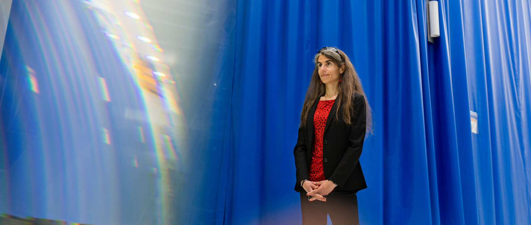 Woman in front of a blue curtain.