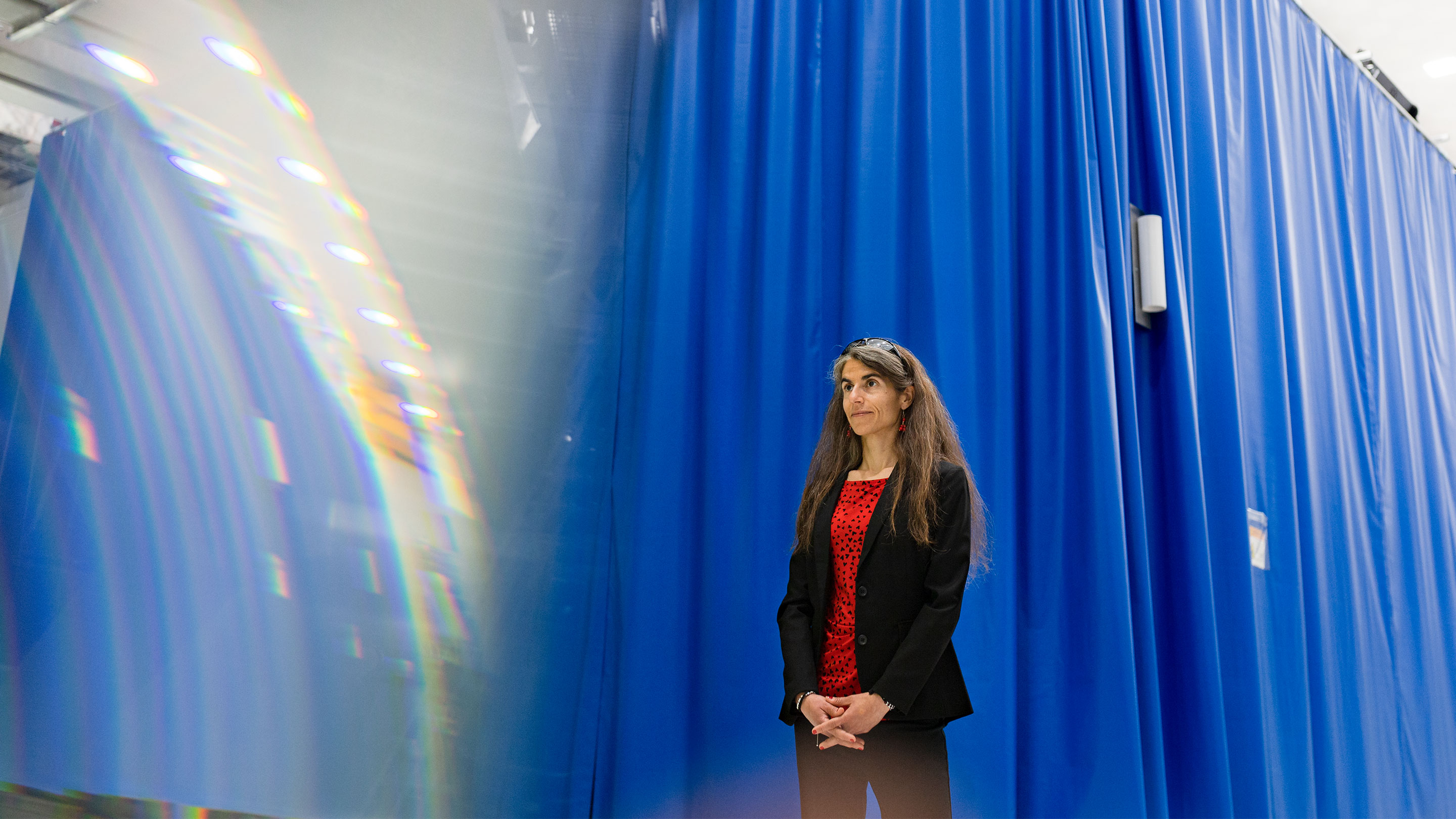 Woman in front of a blue curtain.