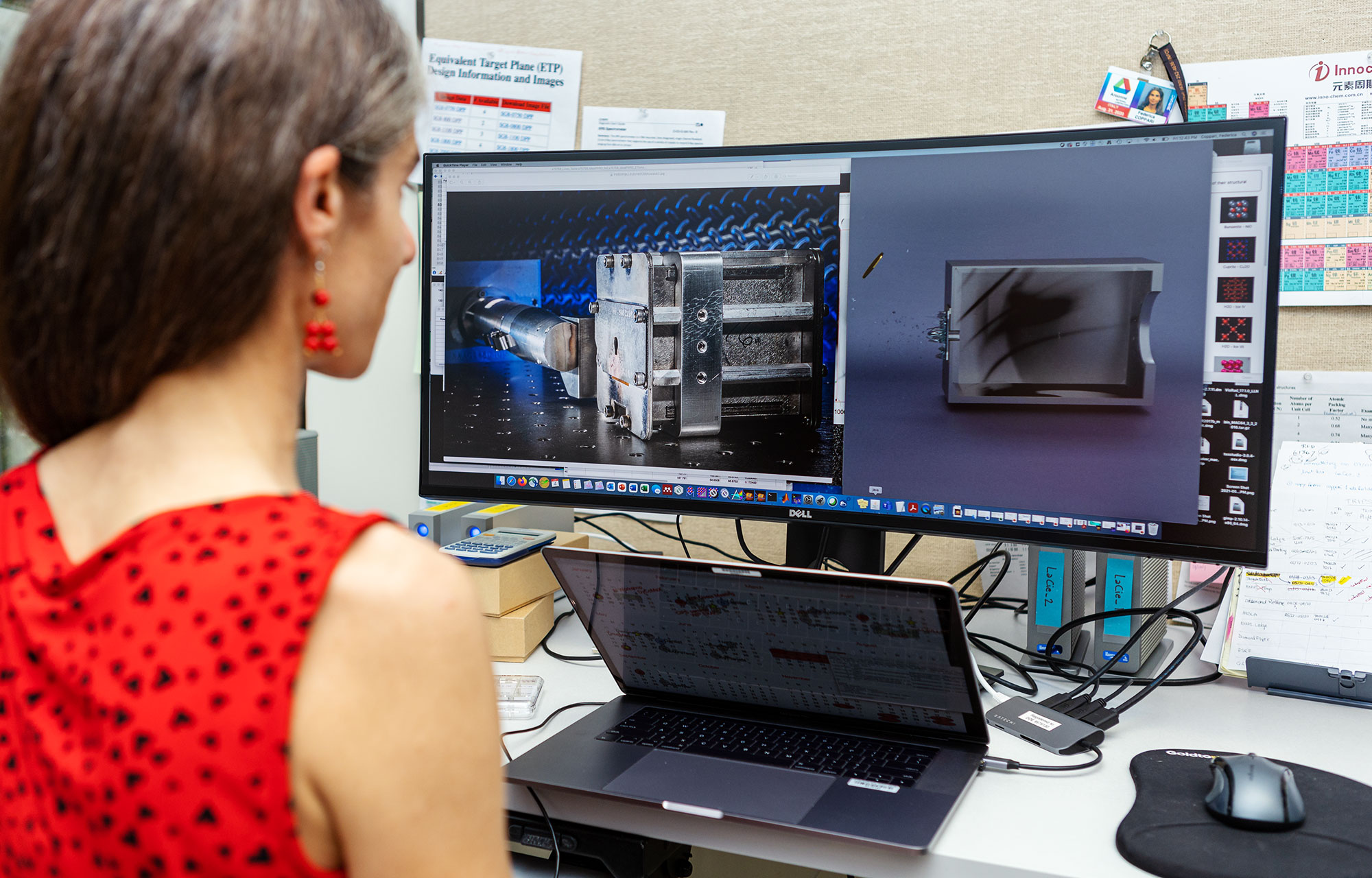 A woman in red views a computer screen with metal devices shown on it.