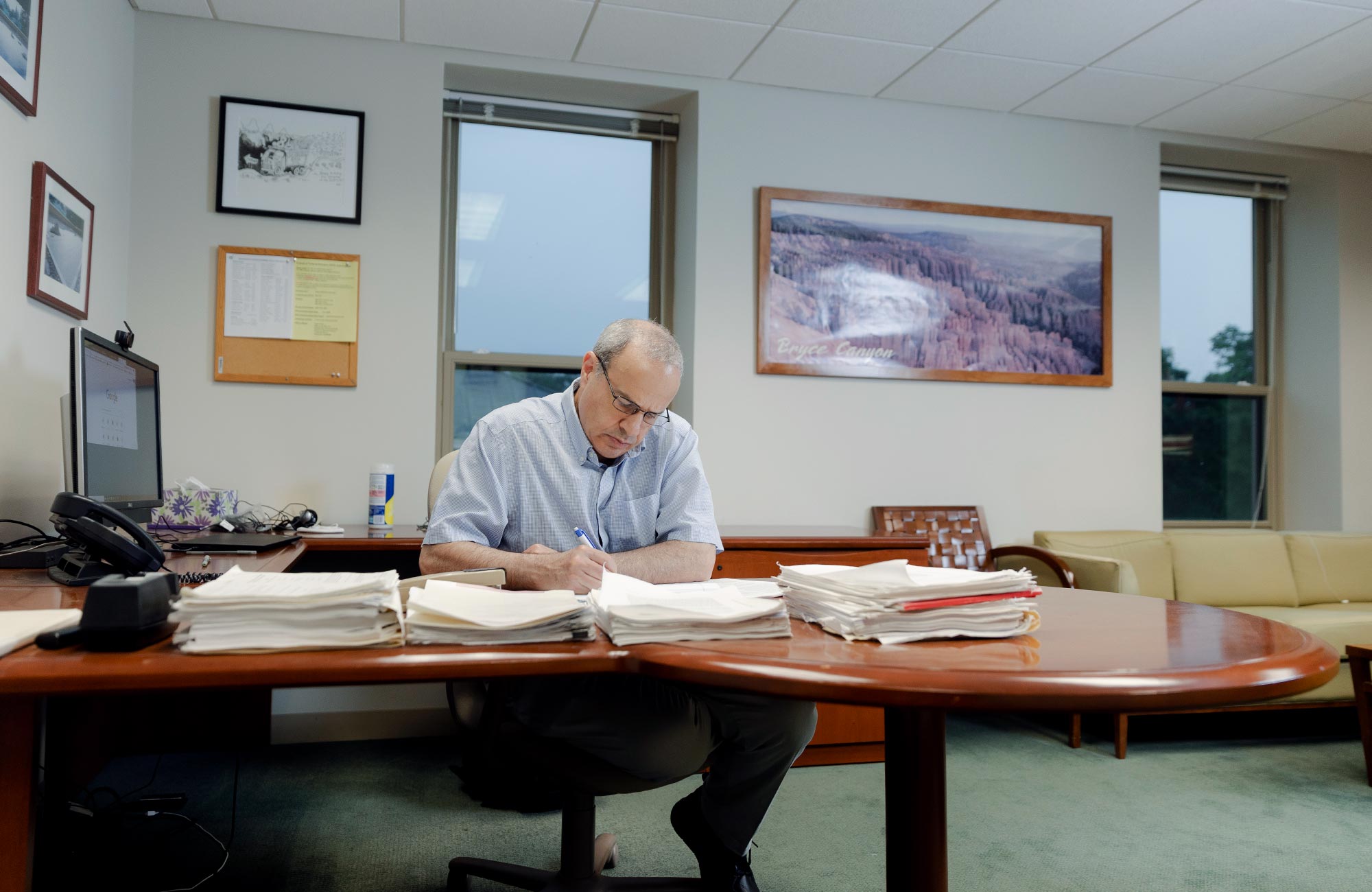 Color photo of Seiberg writing at the desk in his office