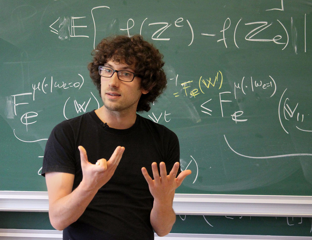 Mathematician Hugo Duminil-Copin standing in front of a chalkboard.