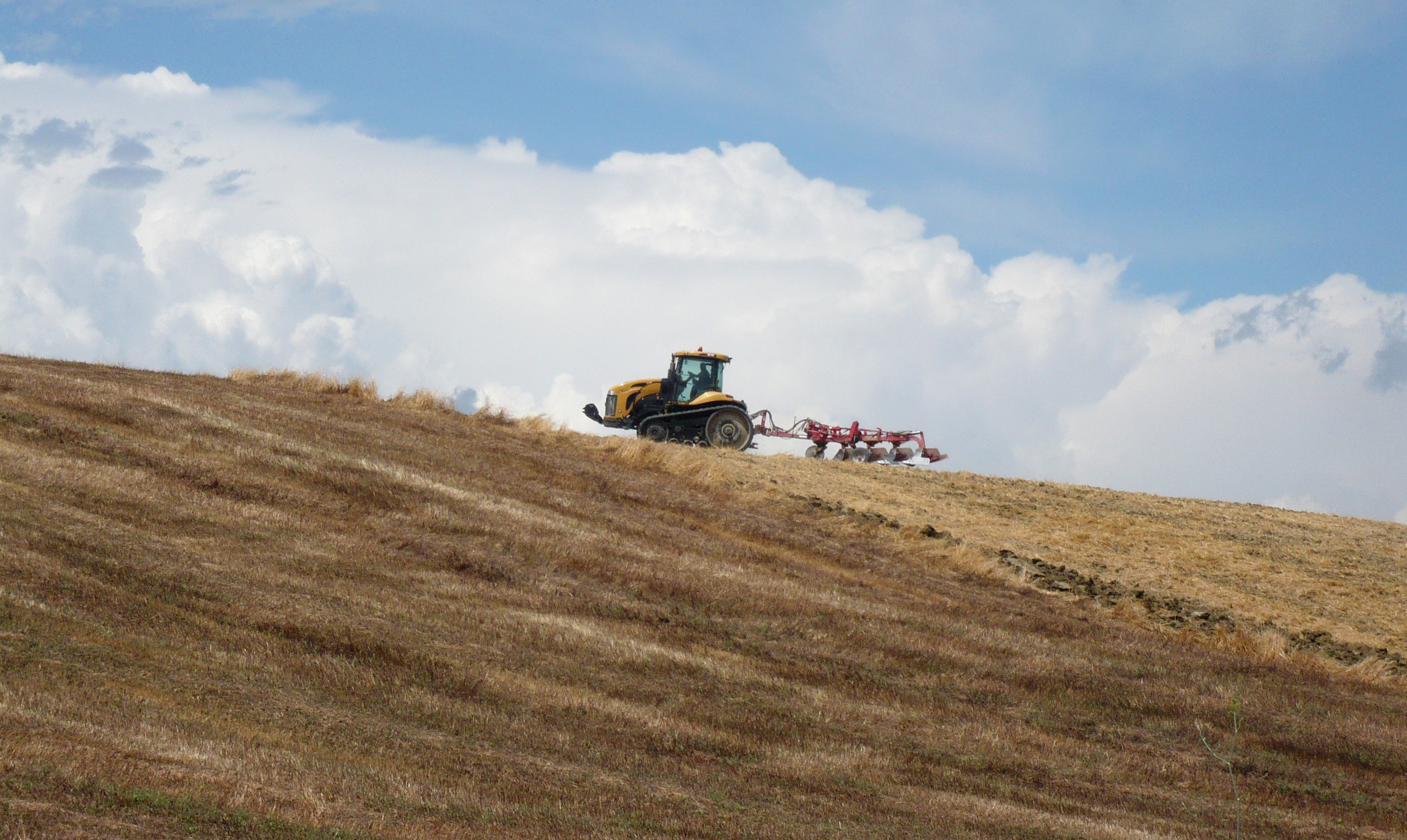 A tractor and a plow on a brown field.