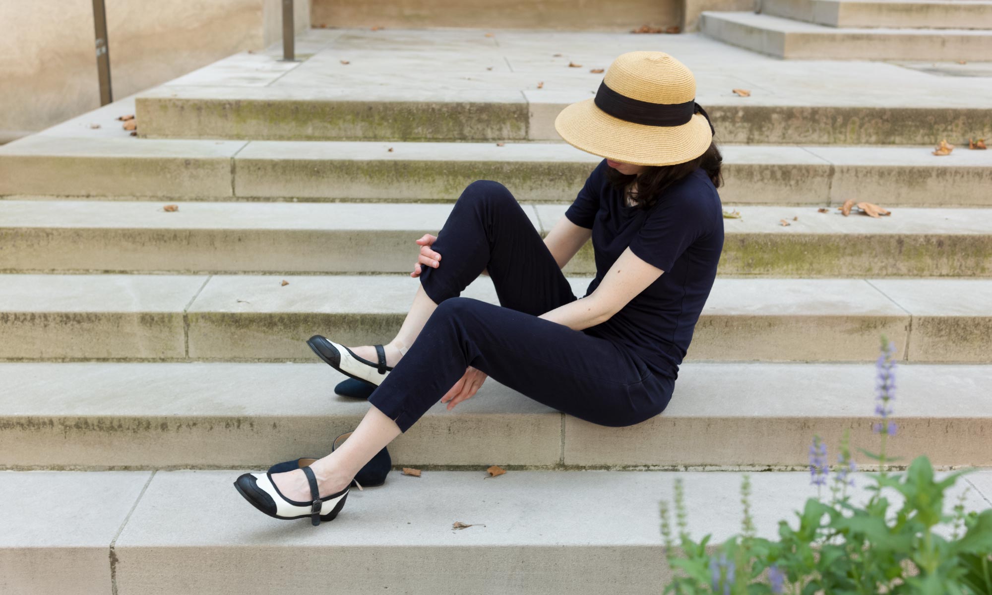 Engelhardt sitting on some stone steps, putting on a pair of black and white dance shoes.