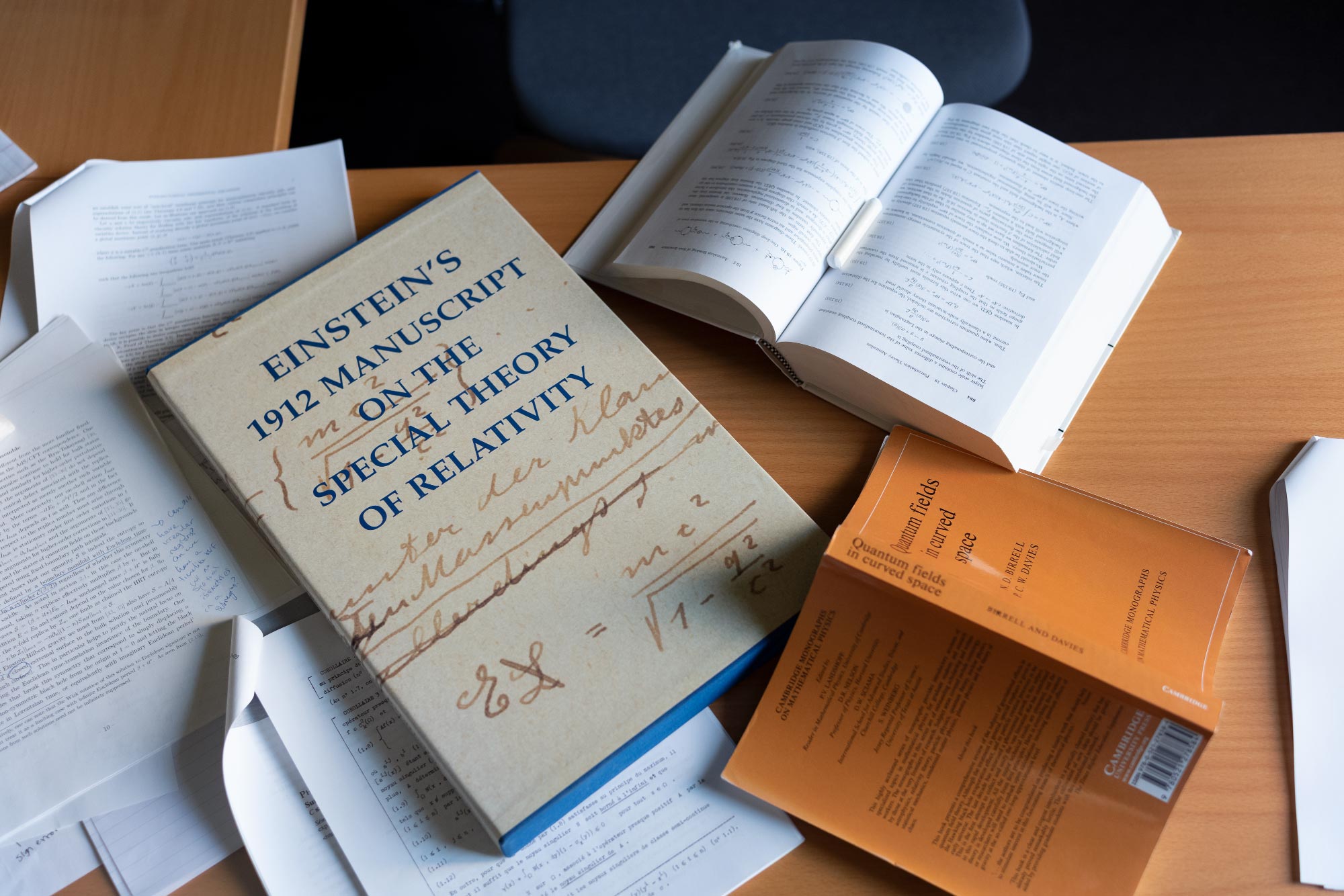 A diptych of two images, one showing Engelhardt drawing on a blackboard and the other showing a pile of books on her desk.