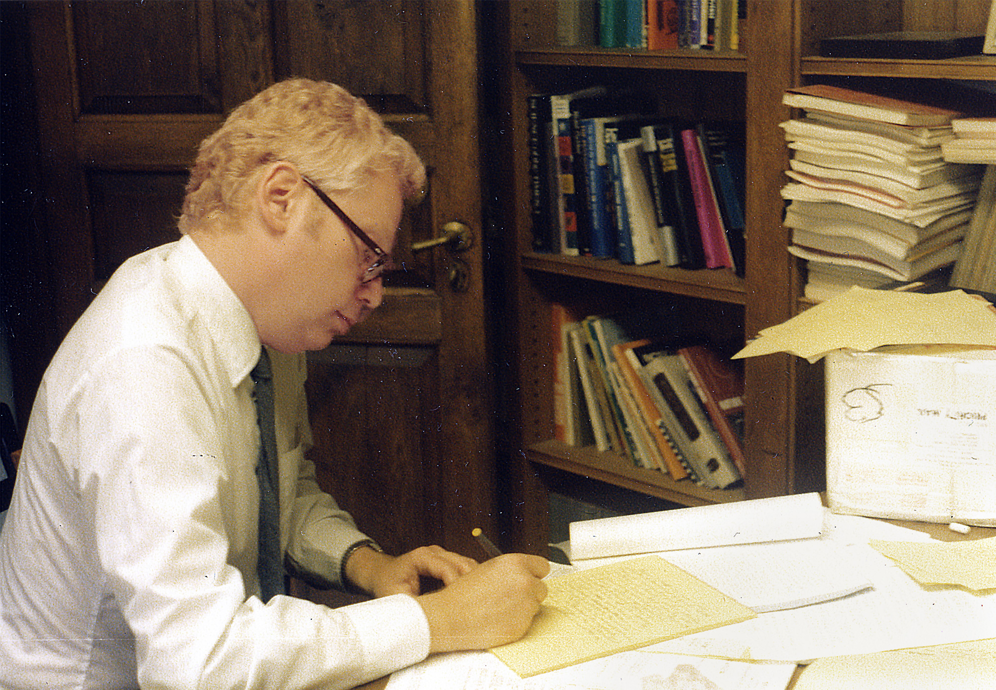 Color photo of a younger Weinberg working at his desk