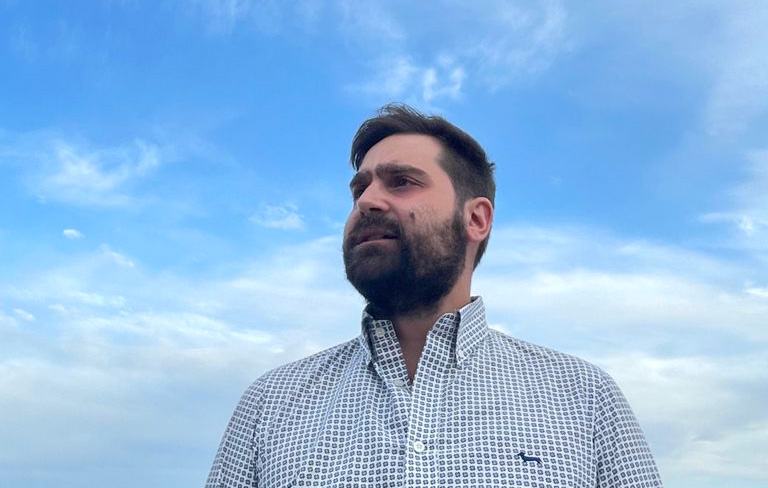 A photo of Gianluca Paolini in a checkered shirt against the sky.