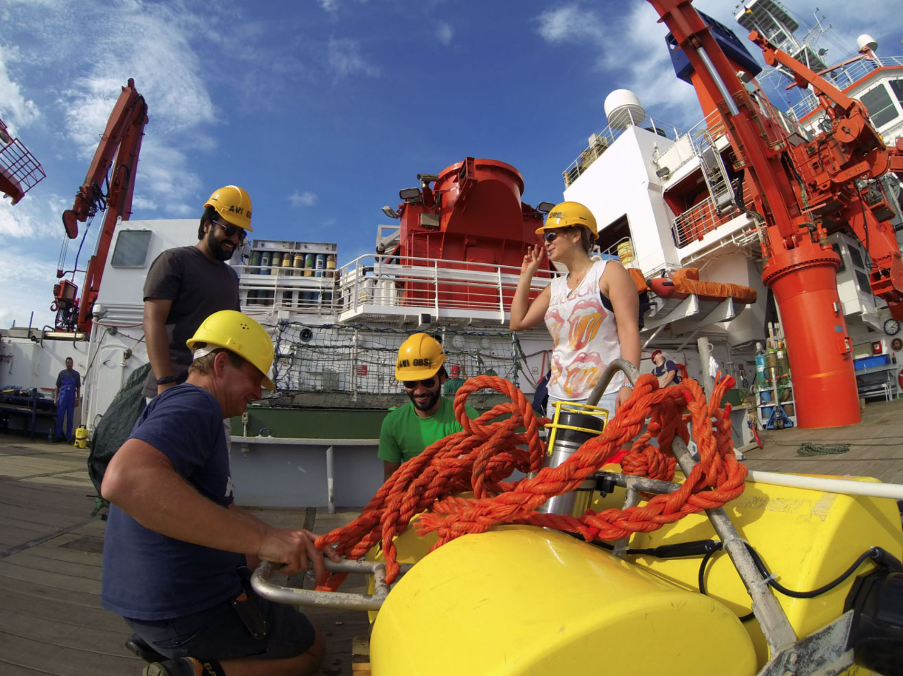 Four people in yellow hard hats on a large vessel.