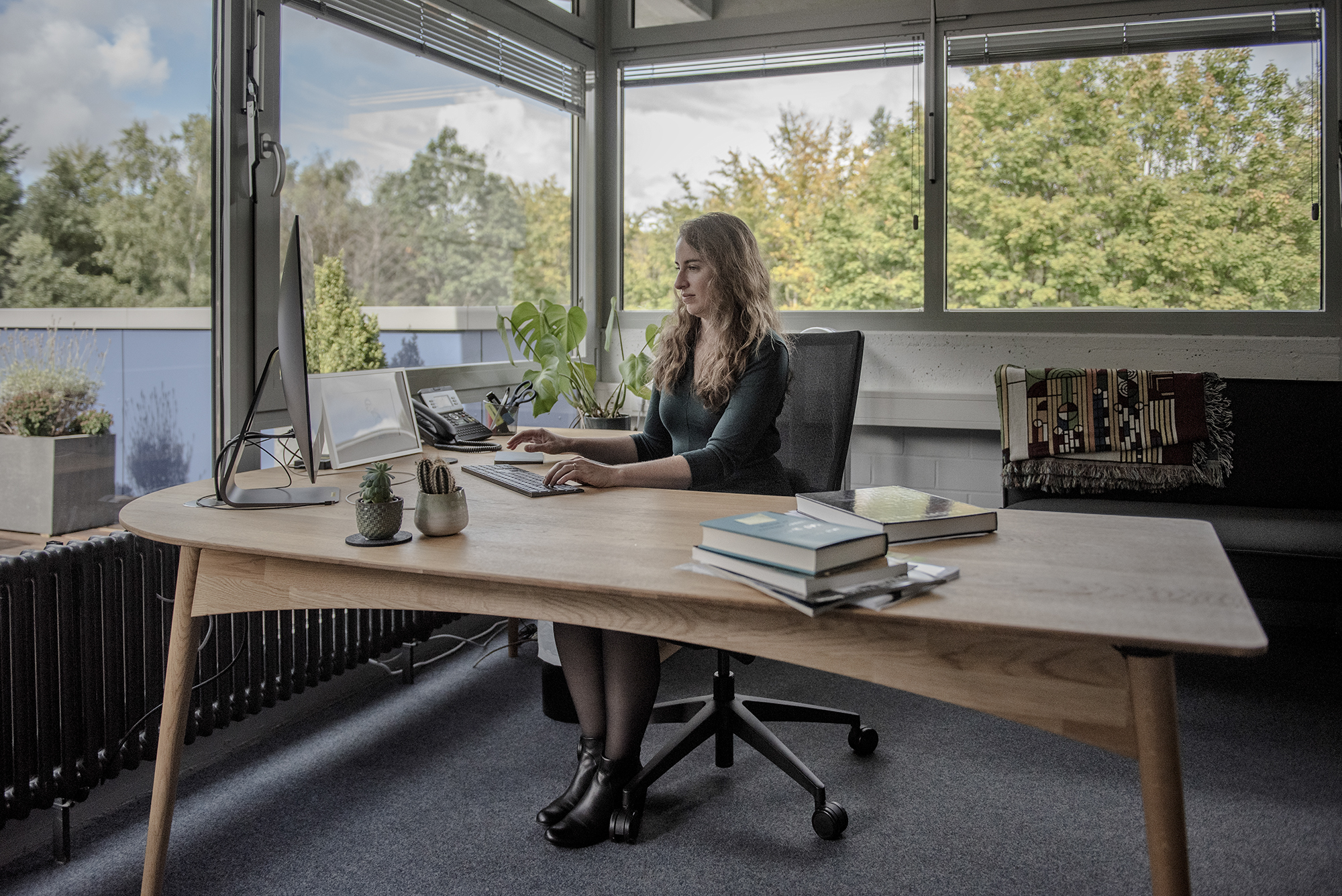 Kreidberg sits at a desk surrounded by glass walls that look out onto trees.