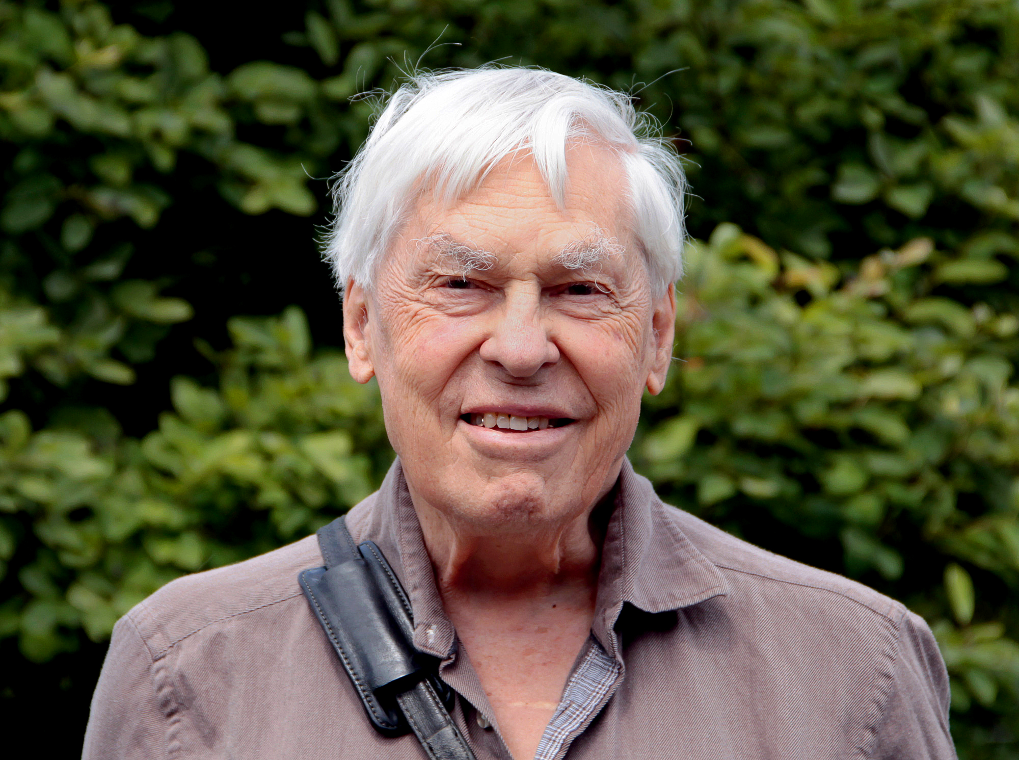 Outdoor photo of Stephen Smale in a brown shirt with in front of trees