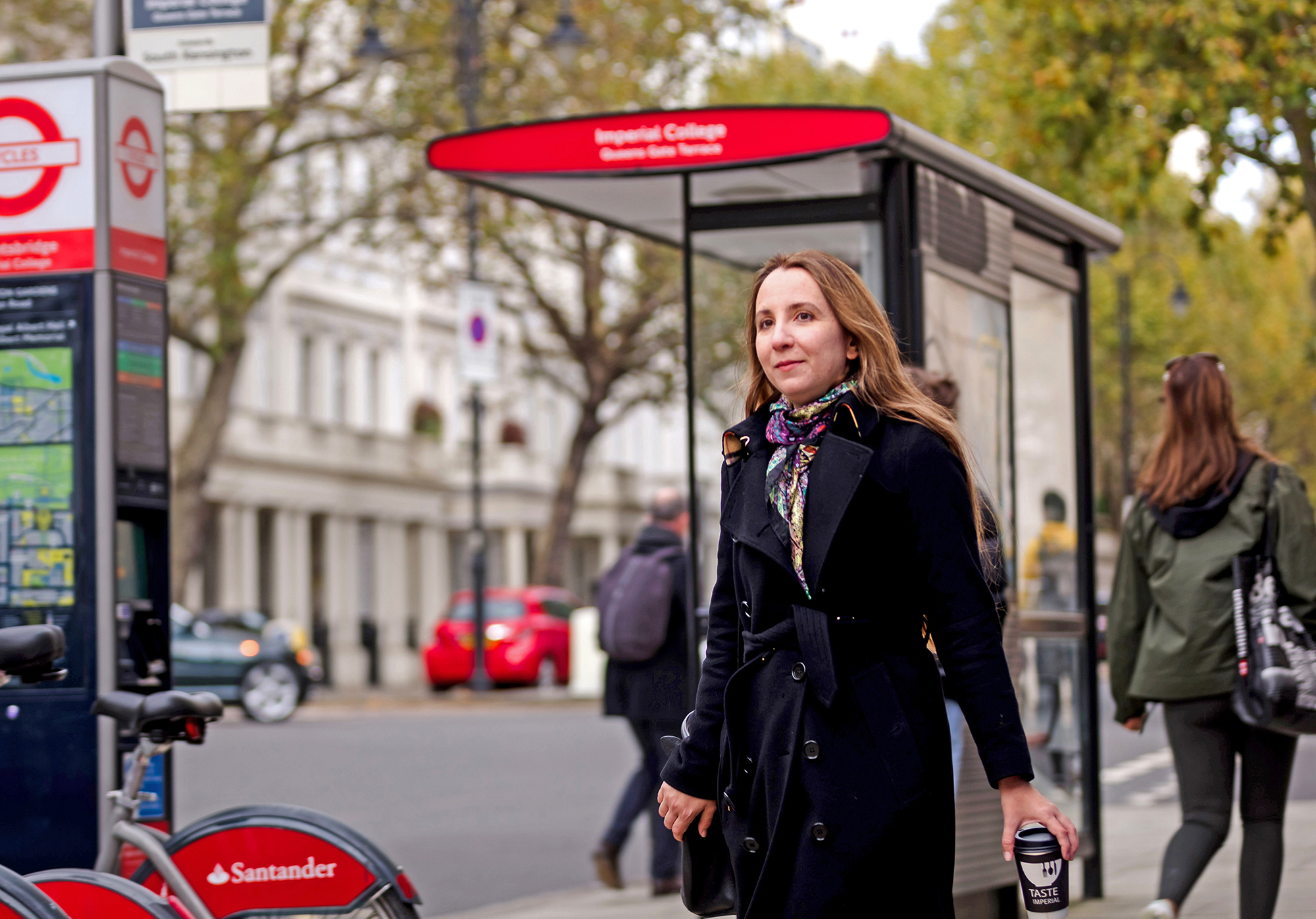 Outdoor photo of Ana Caraiani walking in front of a bus stop in London