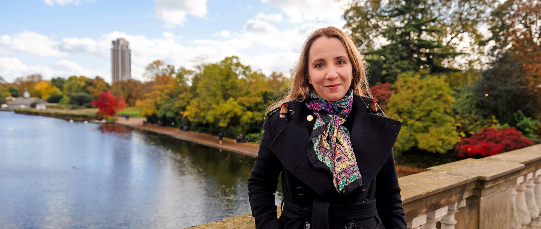 Color photo of Ana Caraiani in a black coat standing on a bridge