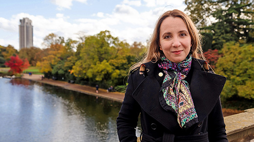 Color photo of Ana Caraiani in a black coat standing on a bridge