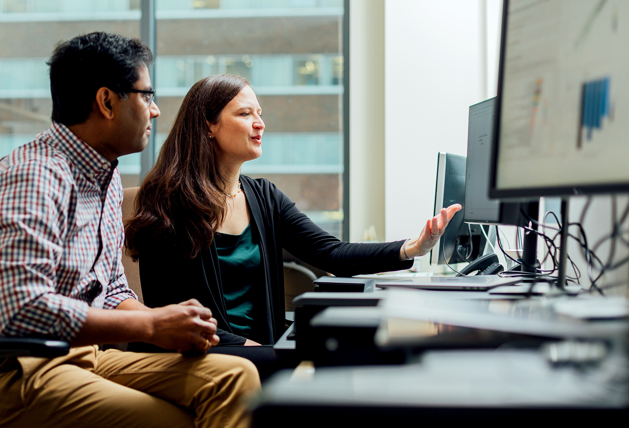 Photo of Anne Carpenter sitting at a computer with Shantanu Singh of the Broad Institute.