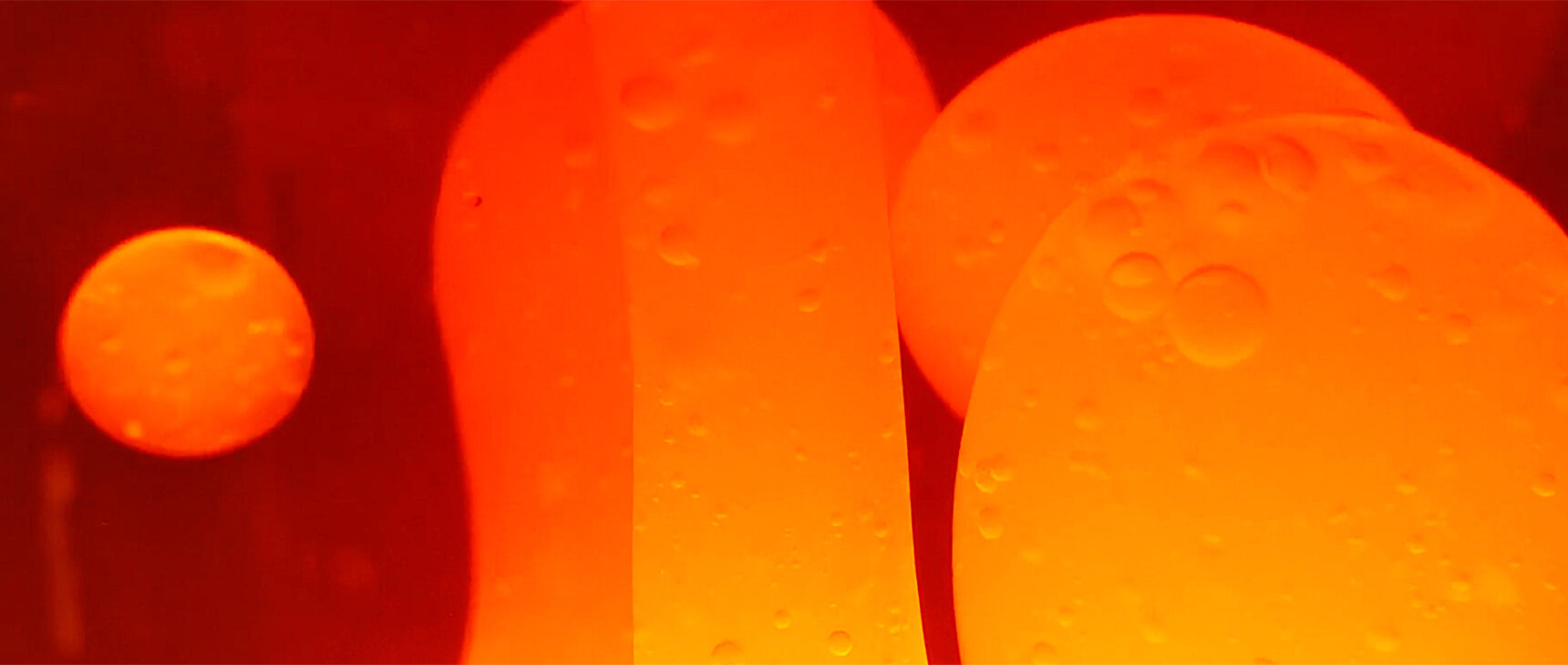 Close-up video of bubbles in a lava lamp moving and splitting under the influence of heat.