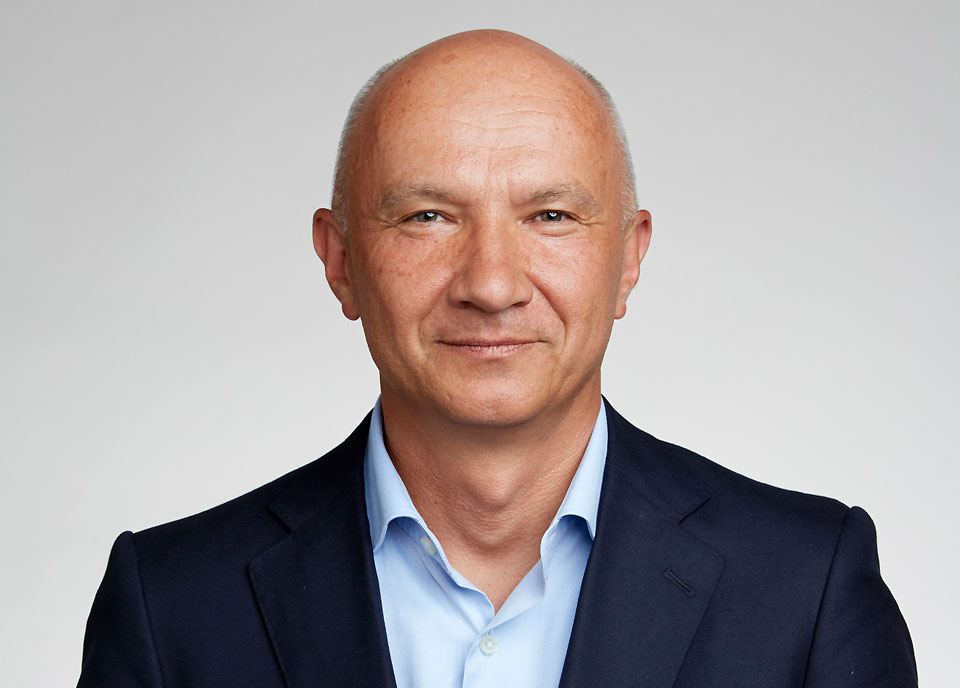 Photo of Artur Ekert in a black blazer with a white background