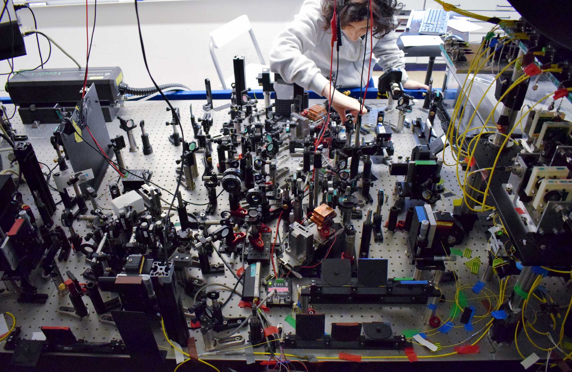 Photo of Valeria Saggio, bent over and working on a table of complex machinery