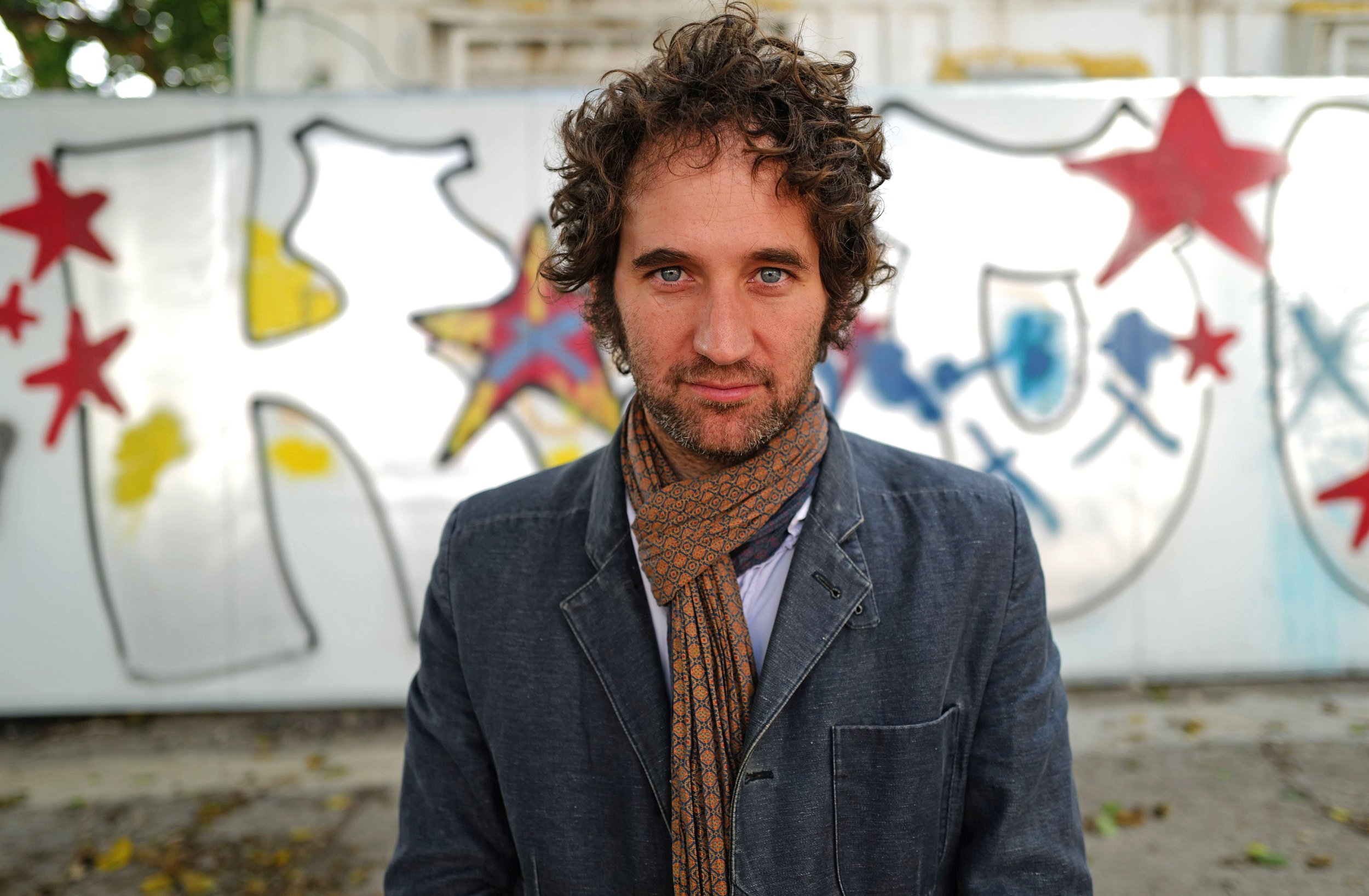 Outdoor photo of Rafael Pass in front of a wall with graffiti.