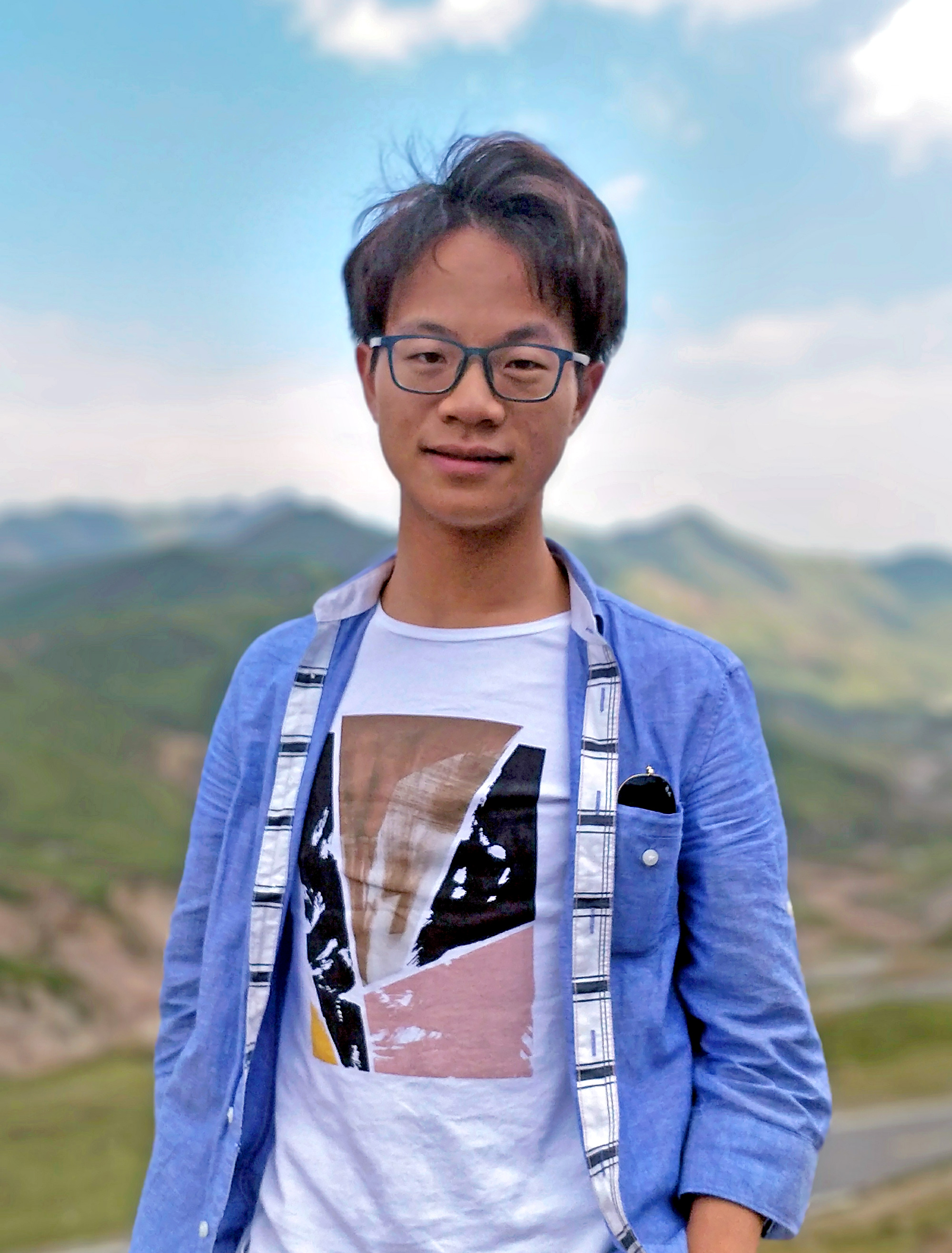 Outdoor photo of Yanyi Liu in a front of a hilly landscape.