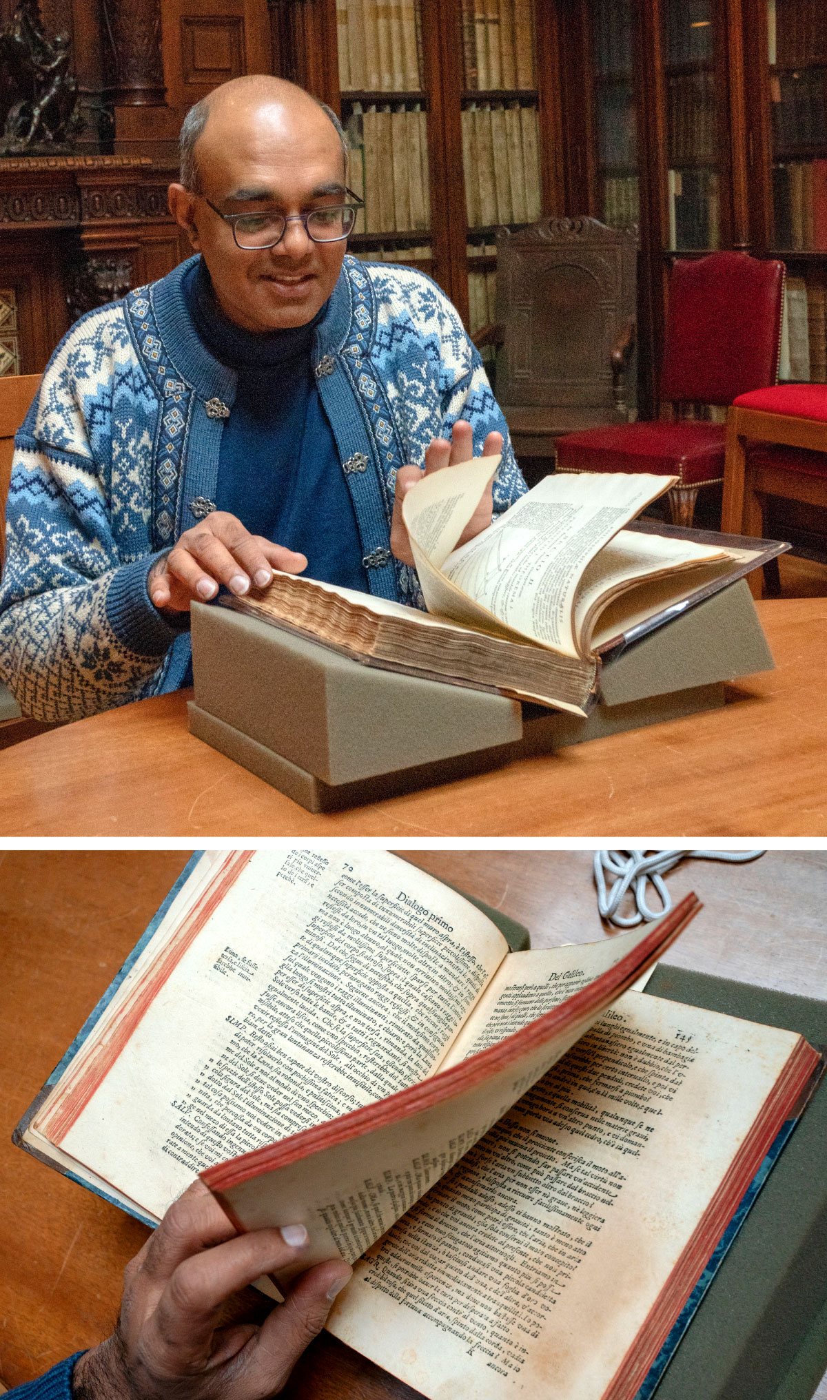 A man smiles while flipping through a large, antique book.