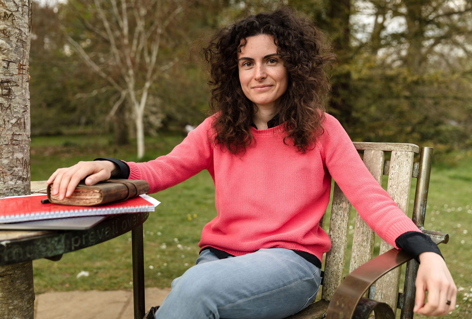 Chiara Marletto, a woman with curly hair sitting down and wearing a pink sweater.