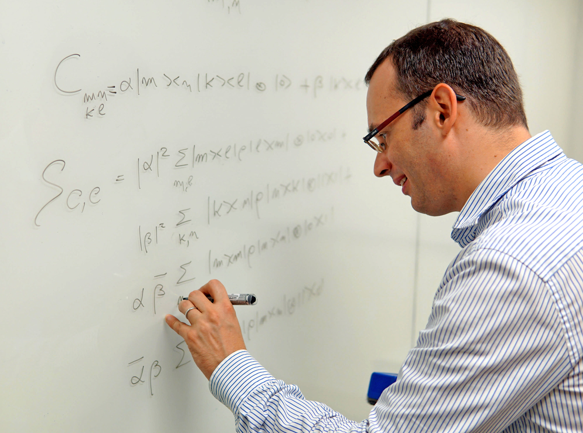 Giulio Chiribella, a man with glasses writing on a white board.