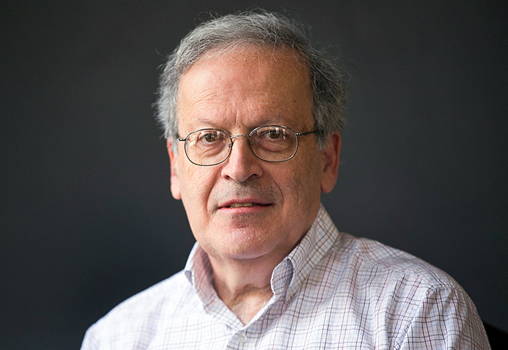 Photo of Leslie Valiant in a checkered shirt in front of a dark background