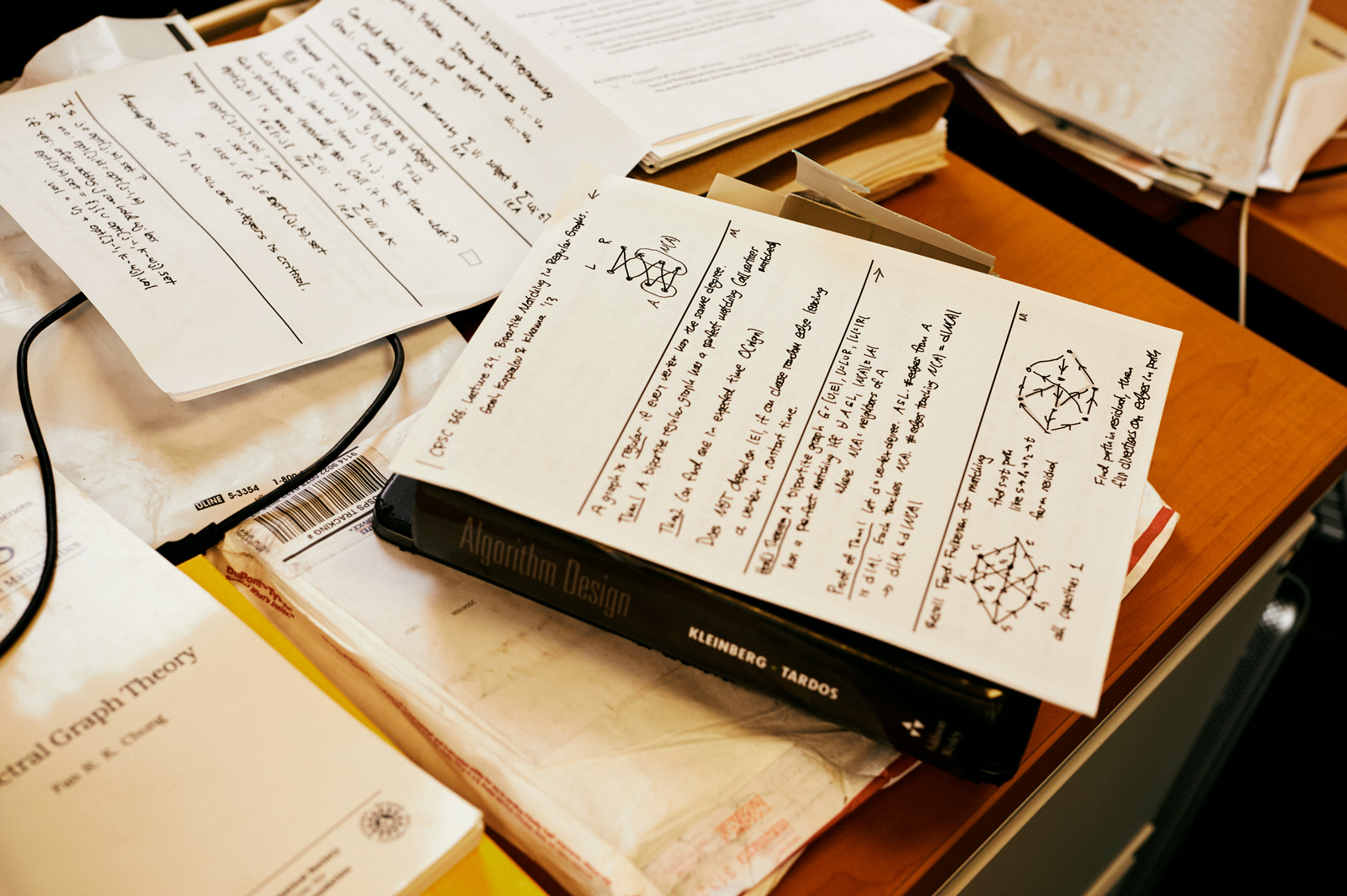 A pile of notes and books on a brown desk