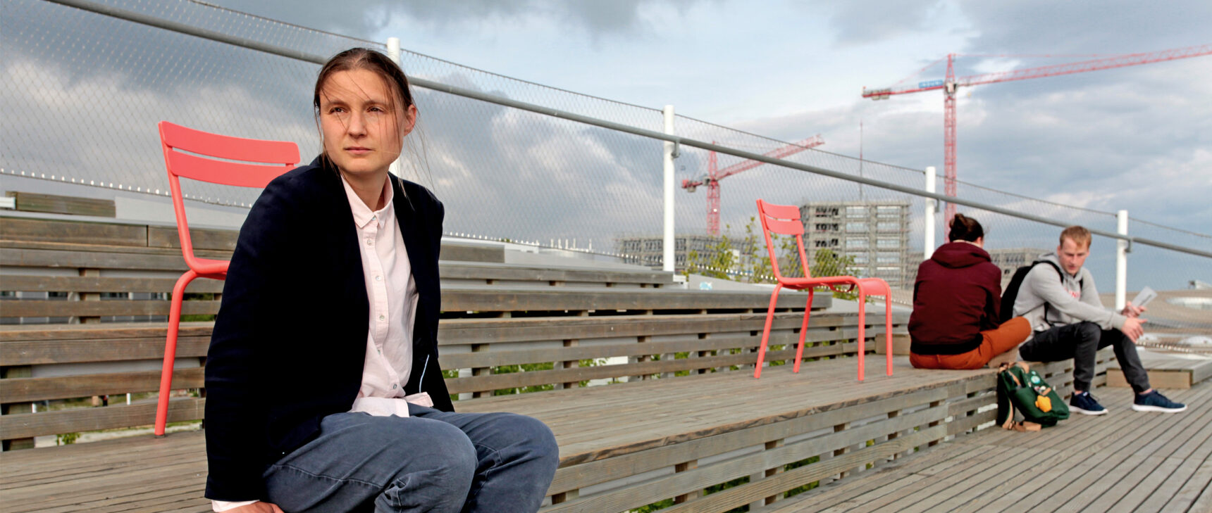 Maryna Viazovska seated on the wooden steps of an amphitheater at the Swiss Federal Institute of Technology Lausanne.