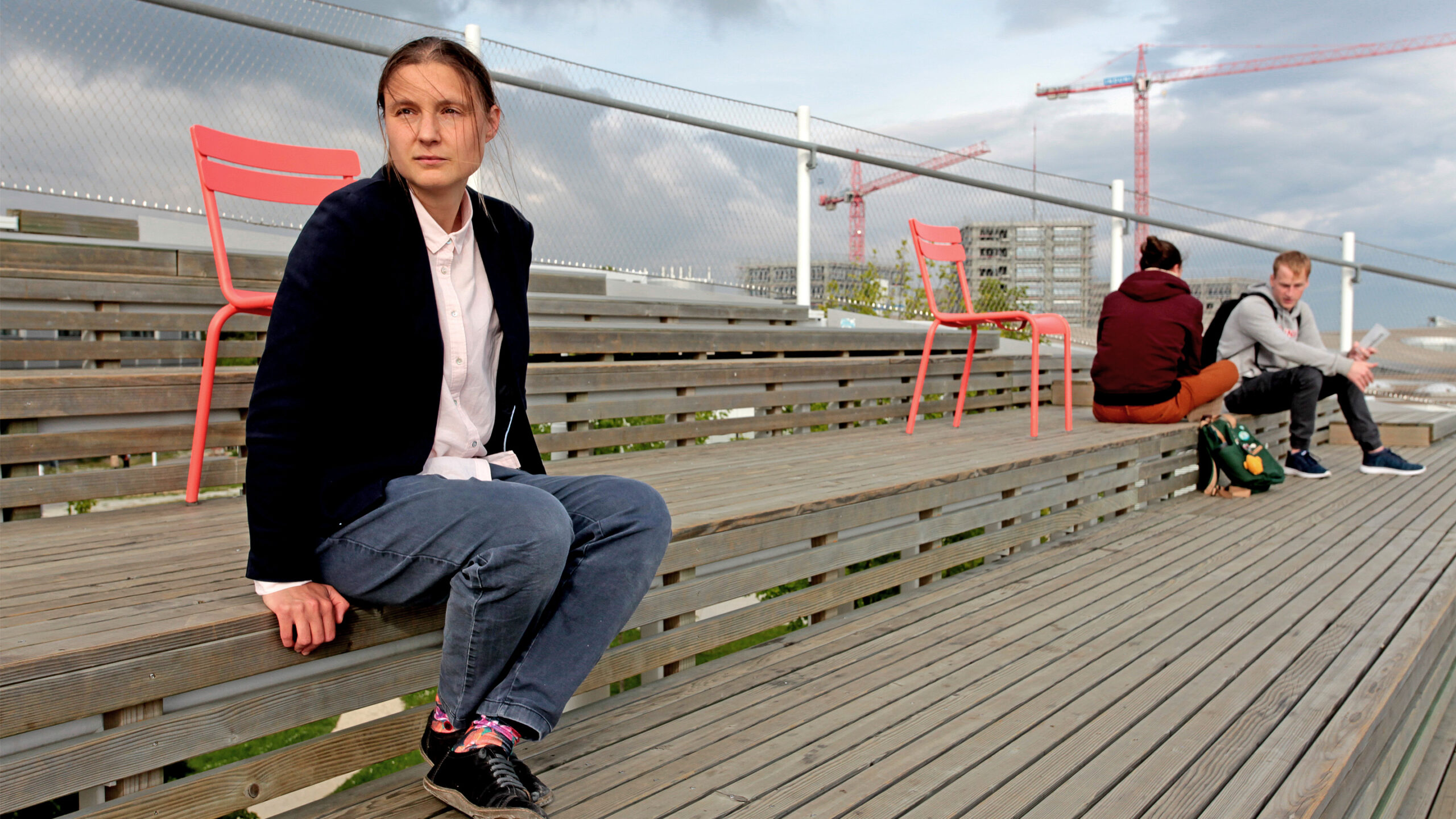 Maryna Viazovska seated on the wooden steps of an amphitheater at the Swiss Federal Institute of Technology Lausanne.