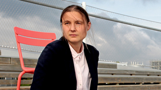 Maryna Viazovska seated on the wooden steps of an amphitheater at the Swiss Federal Institute of Technology Lausanne.