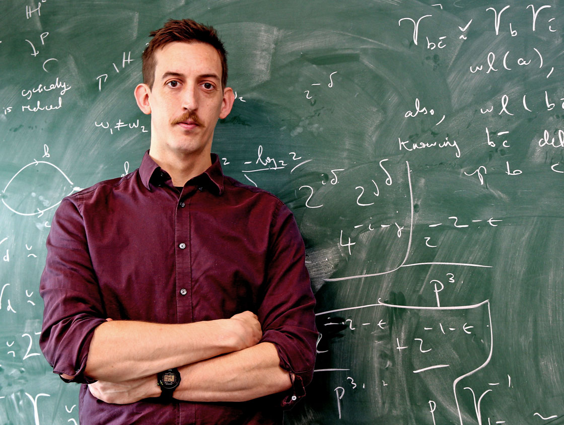 A man with a mustache in front of a chalkboard.