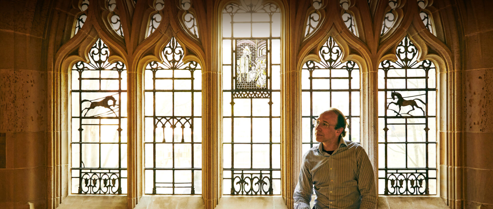 Daniel Spielman sits in front of an elaborate window at Yale University