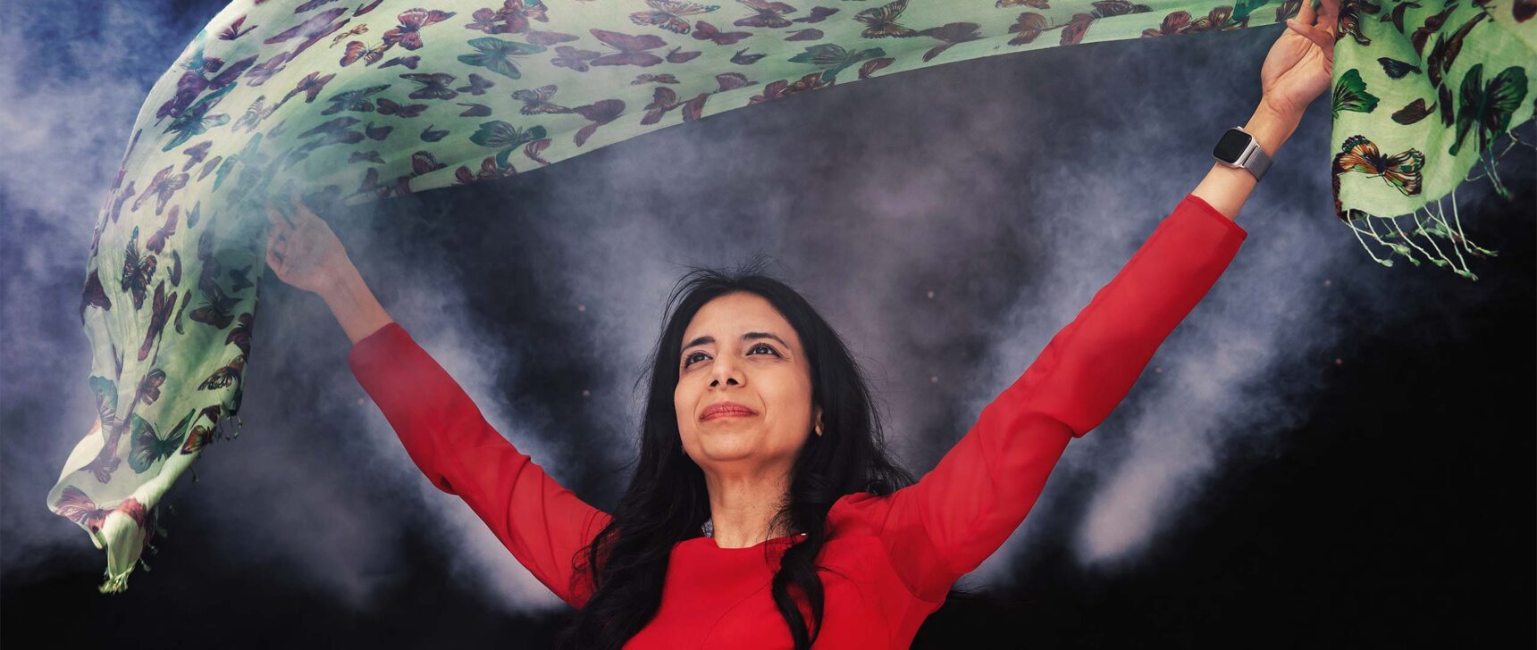 Anima Anandkumar in a red dress holds a green cloth over her head