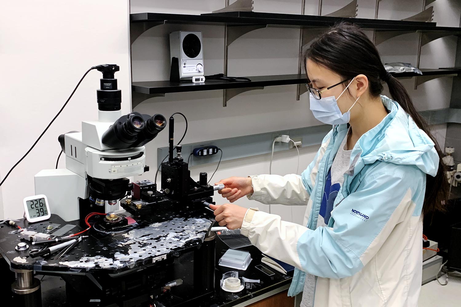 photo showing a female graduate student twiddling the dials on an optical positioning stage