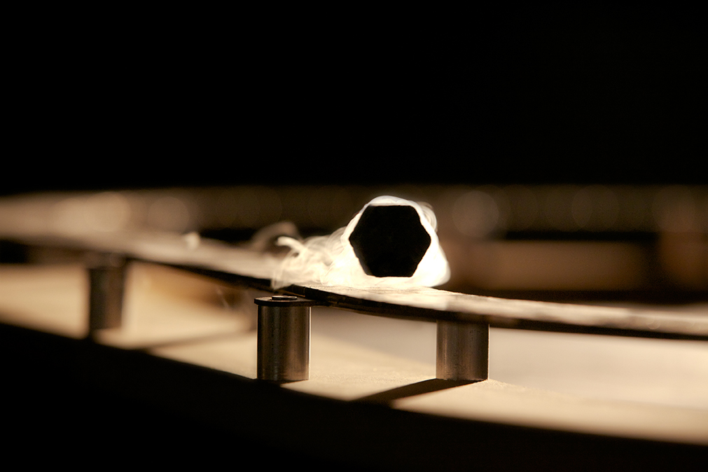 A hexagonal pellet of a ceramic material levitates above a metal bar.