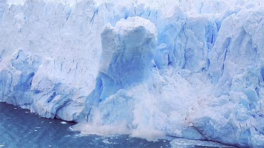 A video of a large chunk of ice breaking off of a glacier and crashing into the ocean.]