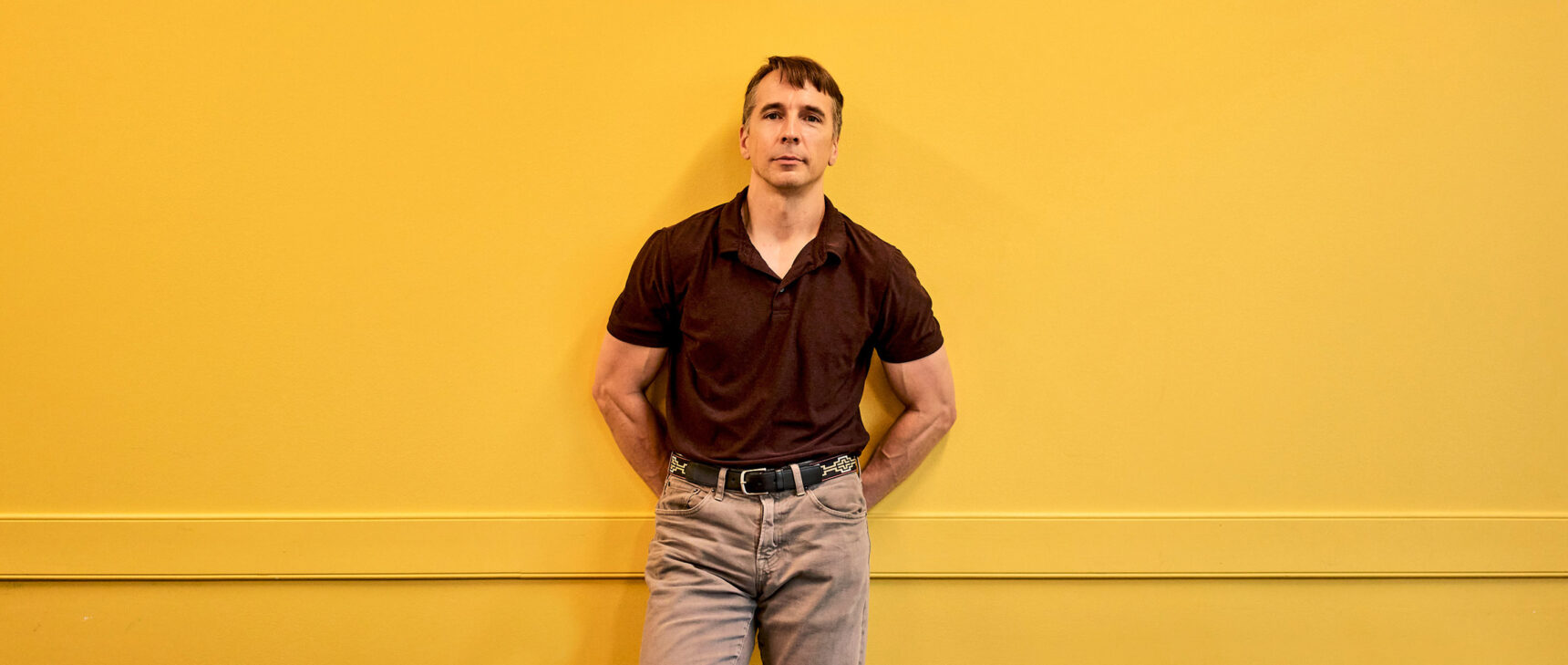 Richard Rusczyk standing in front of a yellow wall in an Art of Problem Solving classroom in San Diego.