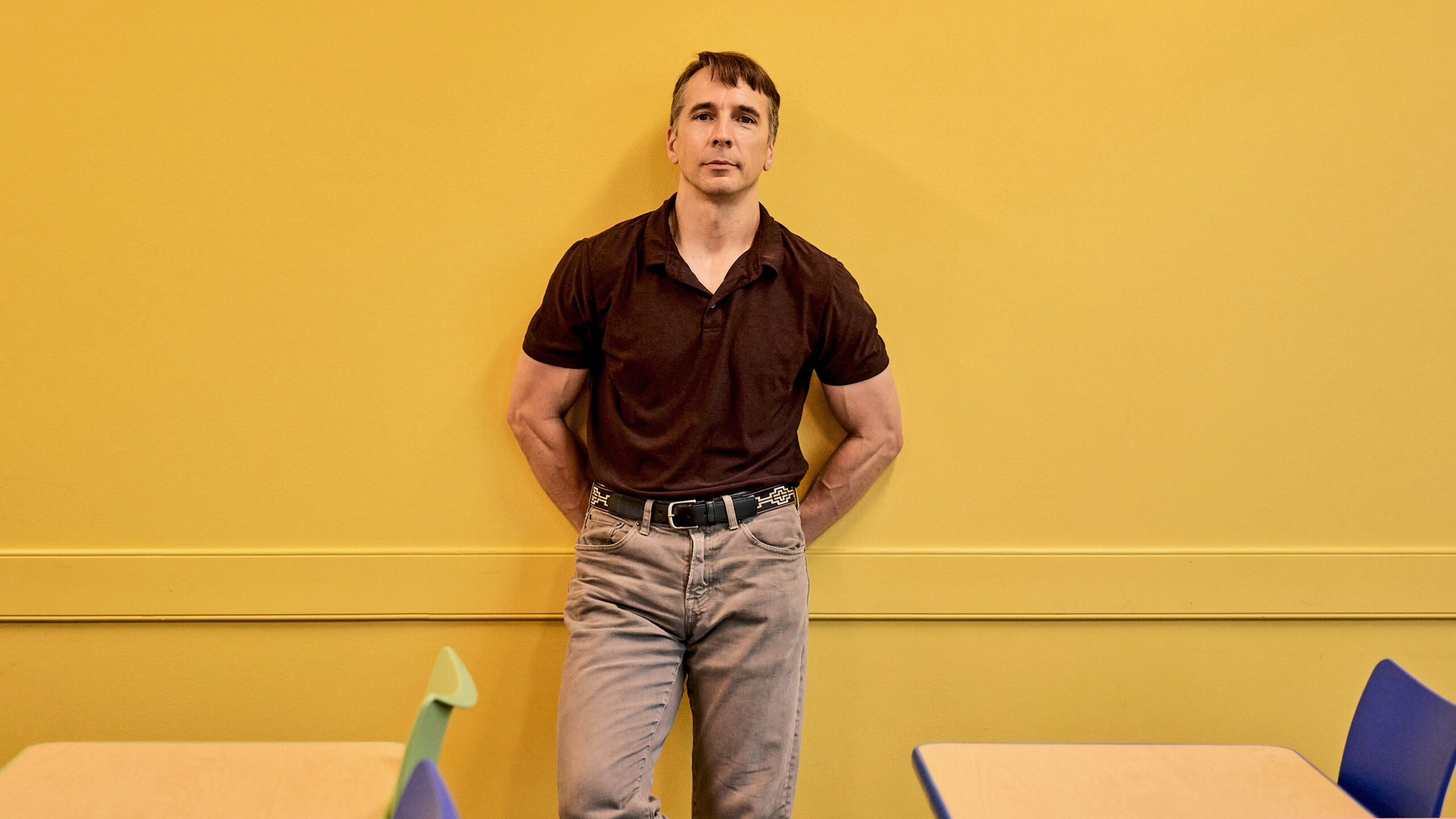 Richard Rusczyk standing in front of a yellow wall in an Art of Problem Solving classroom in San Diego.