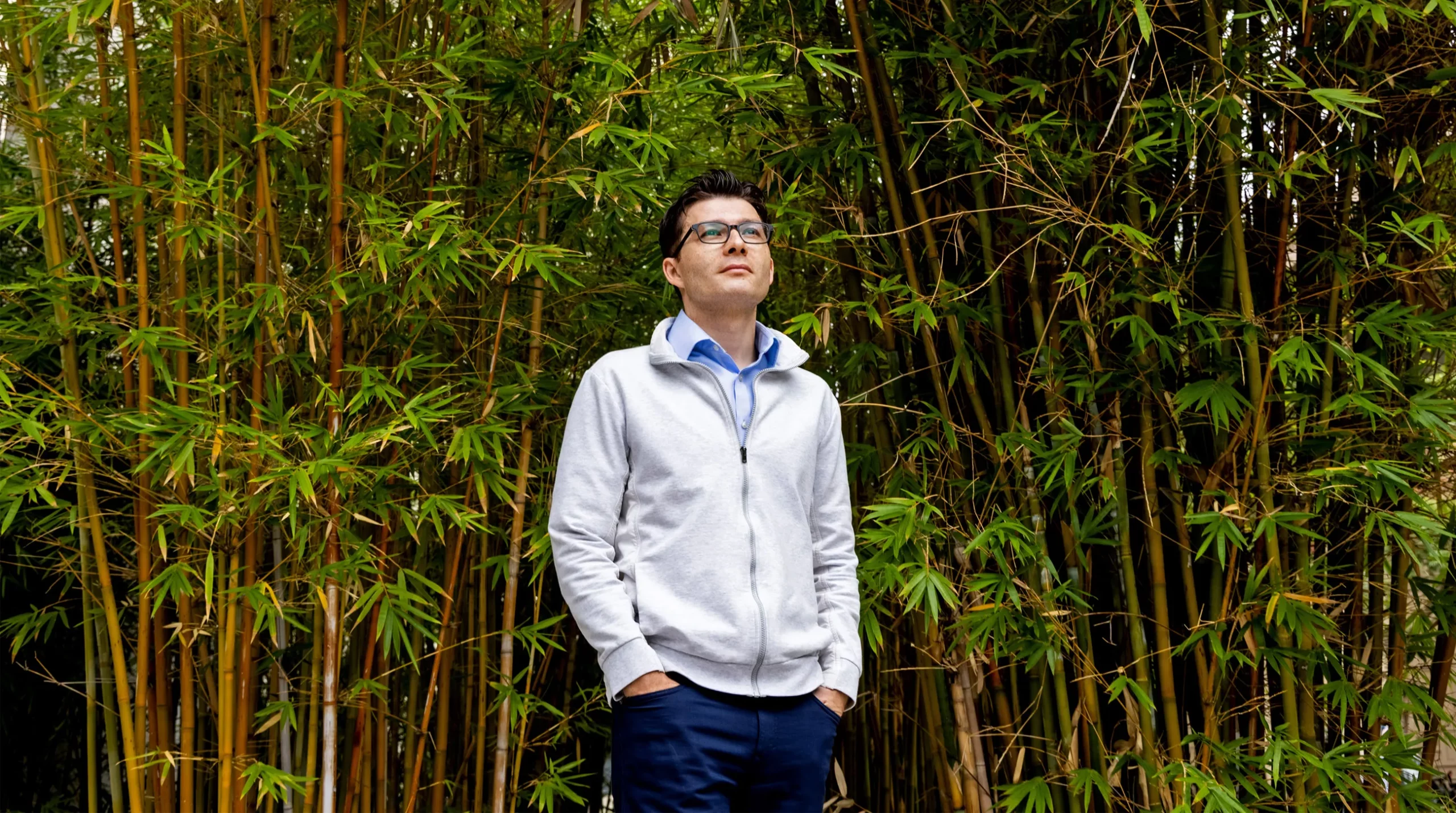 Sergiu Paşca standing outside on a path on the Stanford University campus, with palm trees, bushes and park benches in the background.