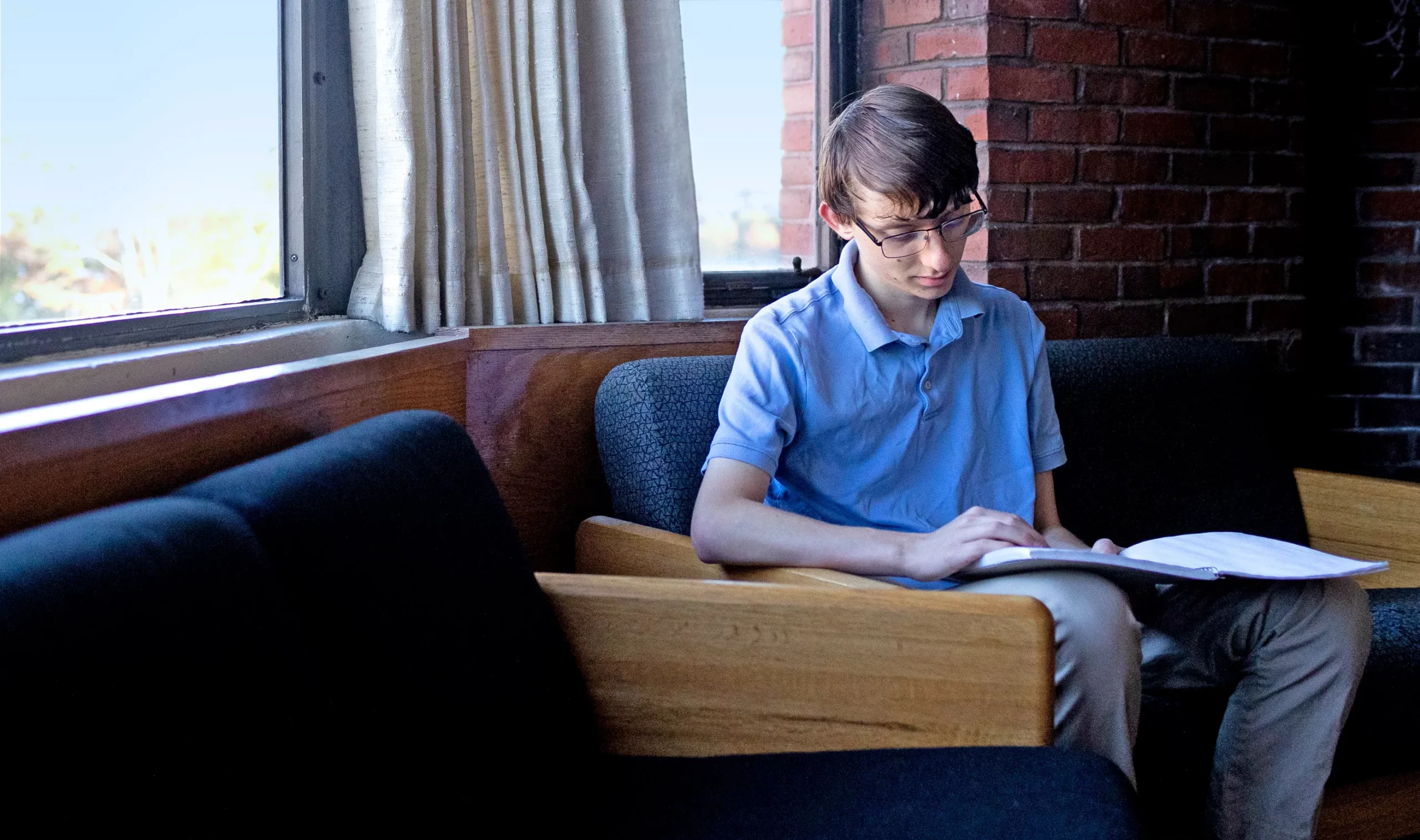 A teenager sitting and reading a notebook.