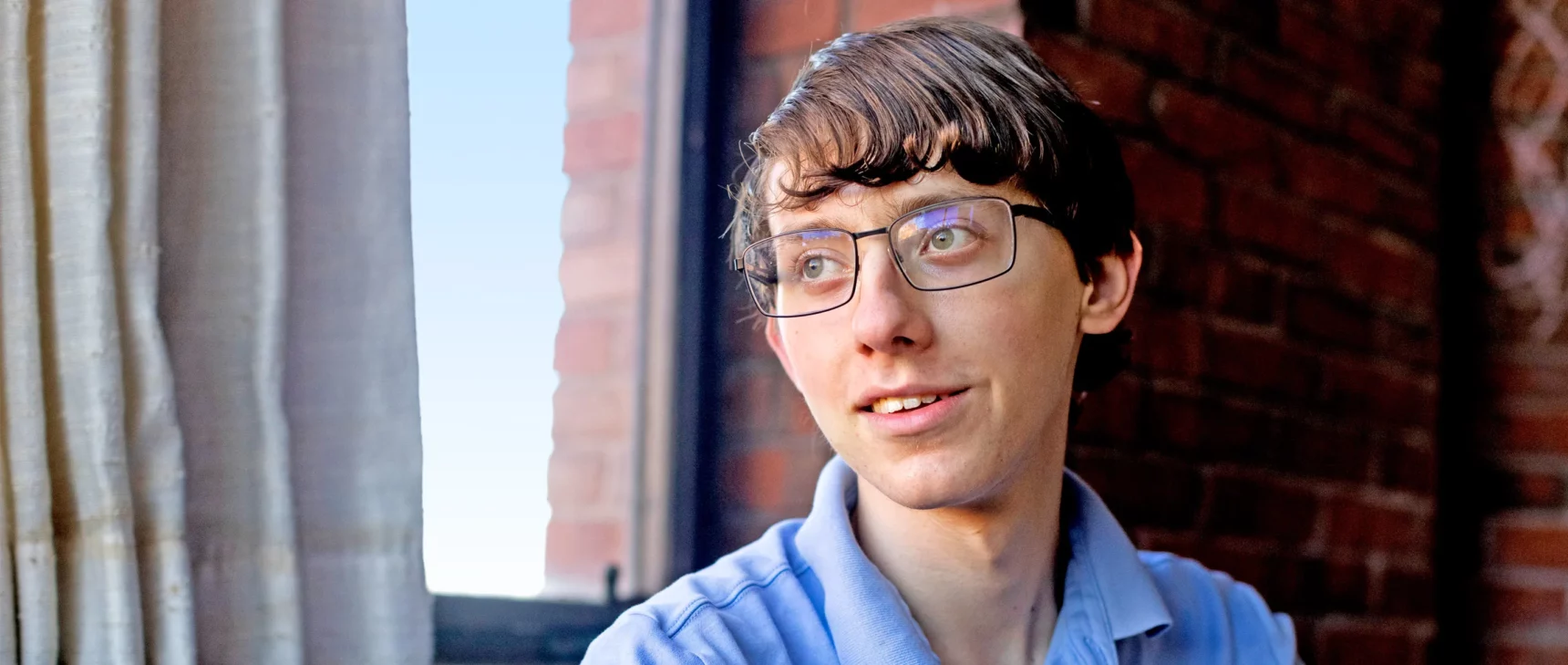 A teenager wearing a blue polo shirt and glasses.