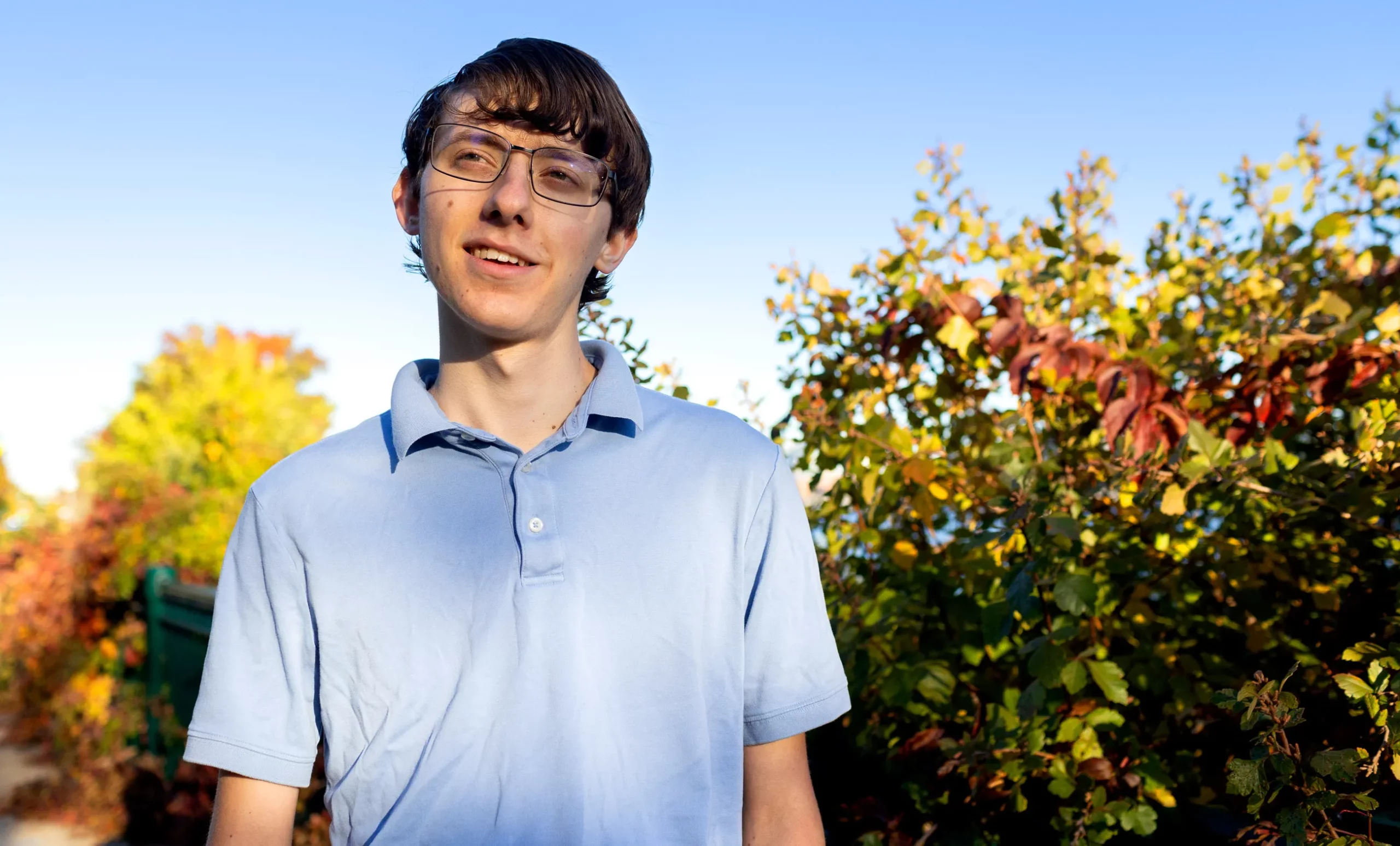 A teenager with a blue shirt outside.