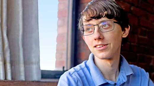 A teenager wearing a blue polo shirt and glasses.