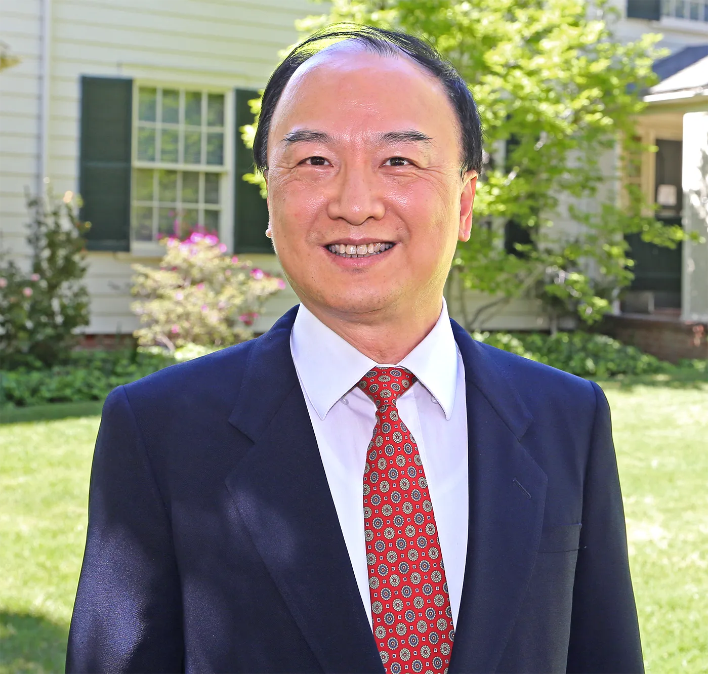 Photograph of a mathematician standing in front of a house