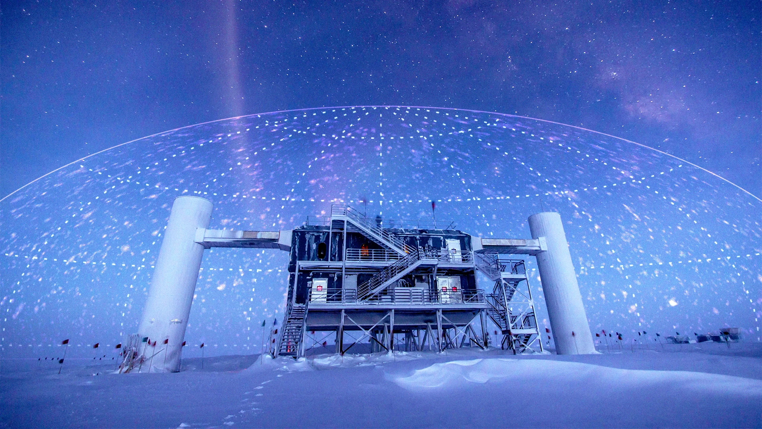 A photo illustration showing a research station in Antarctica with a map plotting neutrinos’ arrival directions imprinted on the sky.